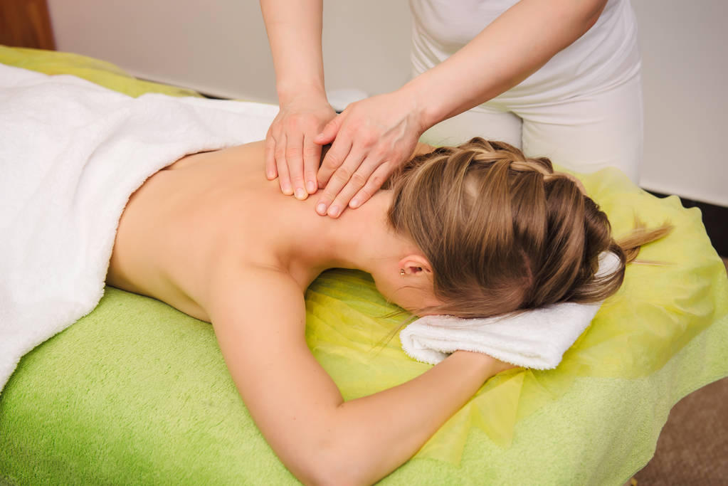 woman having neck and shoulder massage in spa center