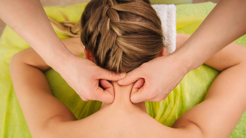 woman having neck and shoulder massage in spa center