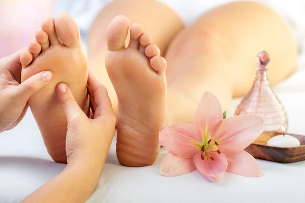close hands doing foot reflexology massage female foot flower candle