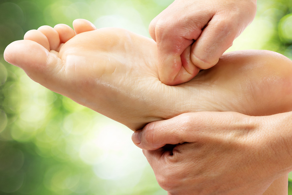 healing foot massage against green background.